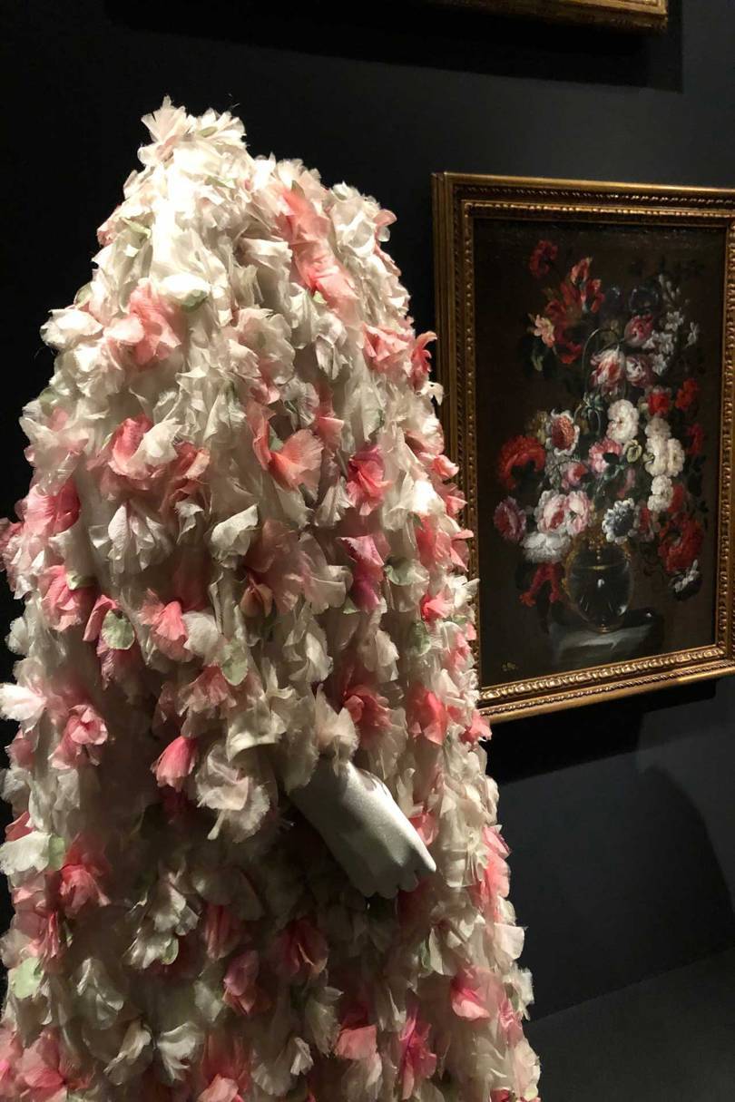 A Balenciaga organza evening coat with floral applications (1964) set against the still-life by Gabriel de la Corte, Flowers in a vase (second-half of the 17th century). Credit: NATASHA COWAN
