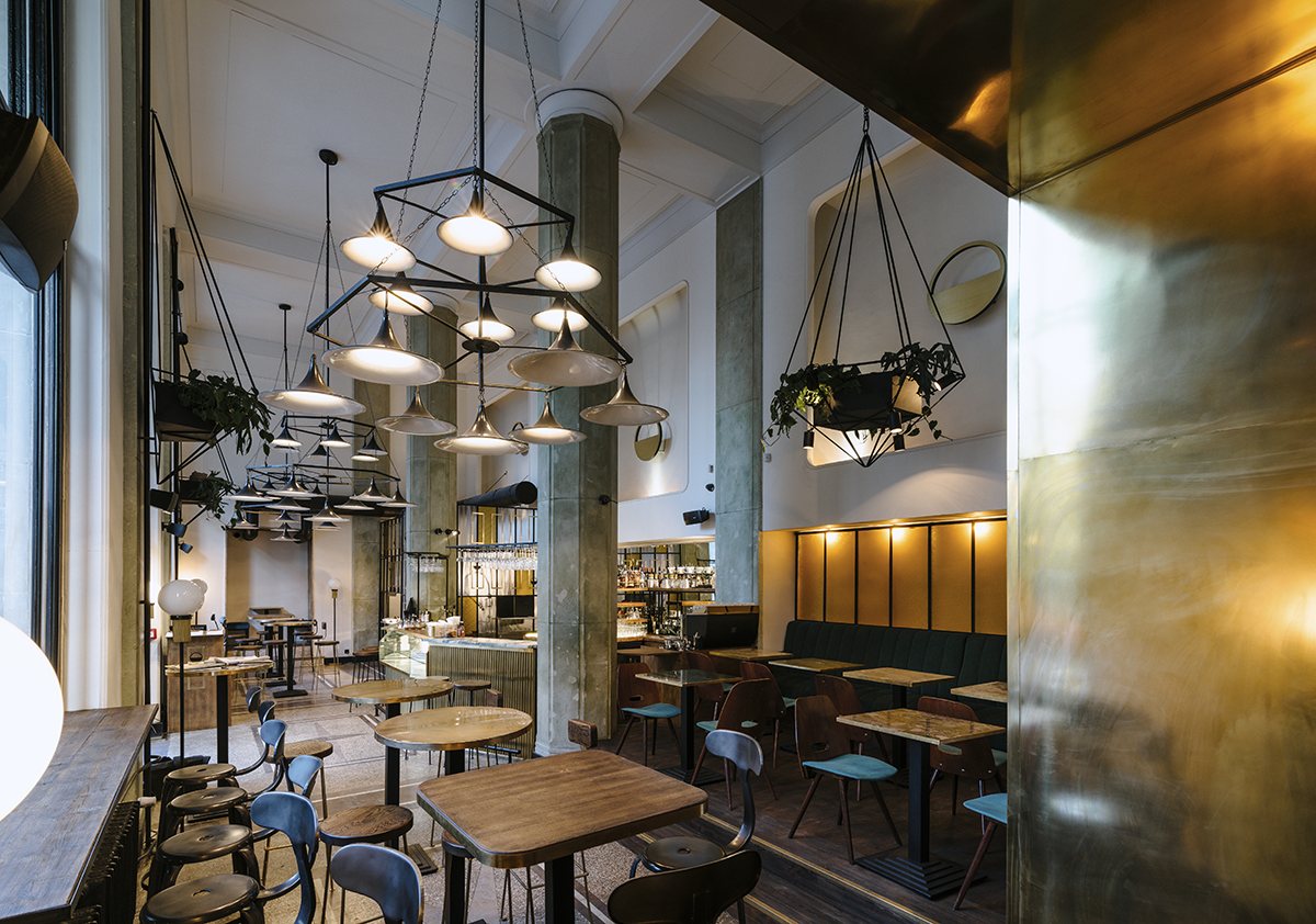 Industrialne wnętrze restauracji Zorza z wysokimi stołami i krzesłami.