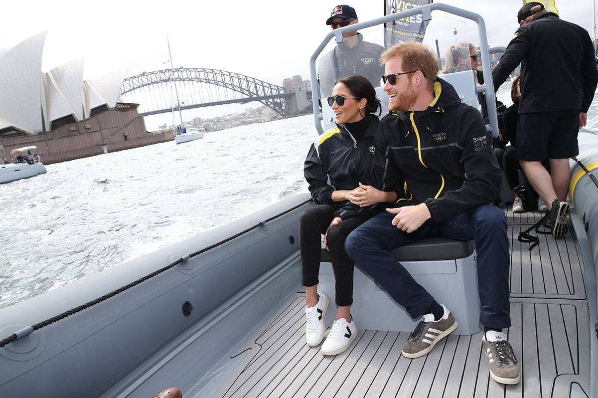 21 października 2018 roku: Książę Harry i Meghan Markle na Sydney Harbour podczas drugiego dnia Invictus Games 2018 w sneakersach Gazelle adidas Originals i Veja V-10.