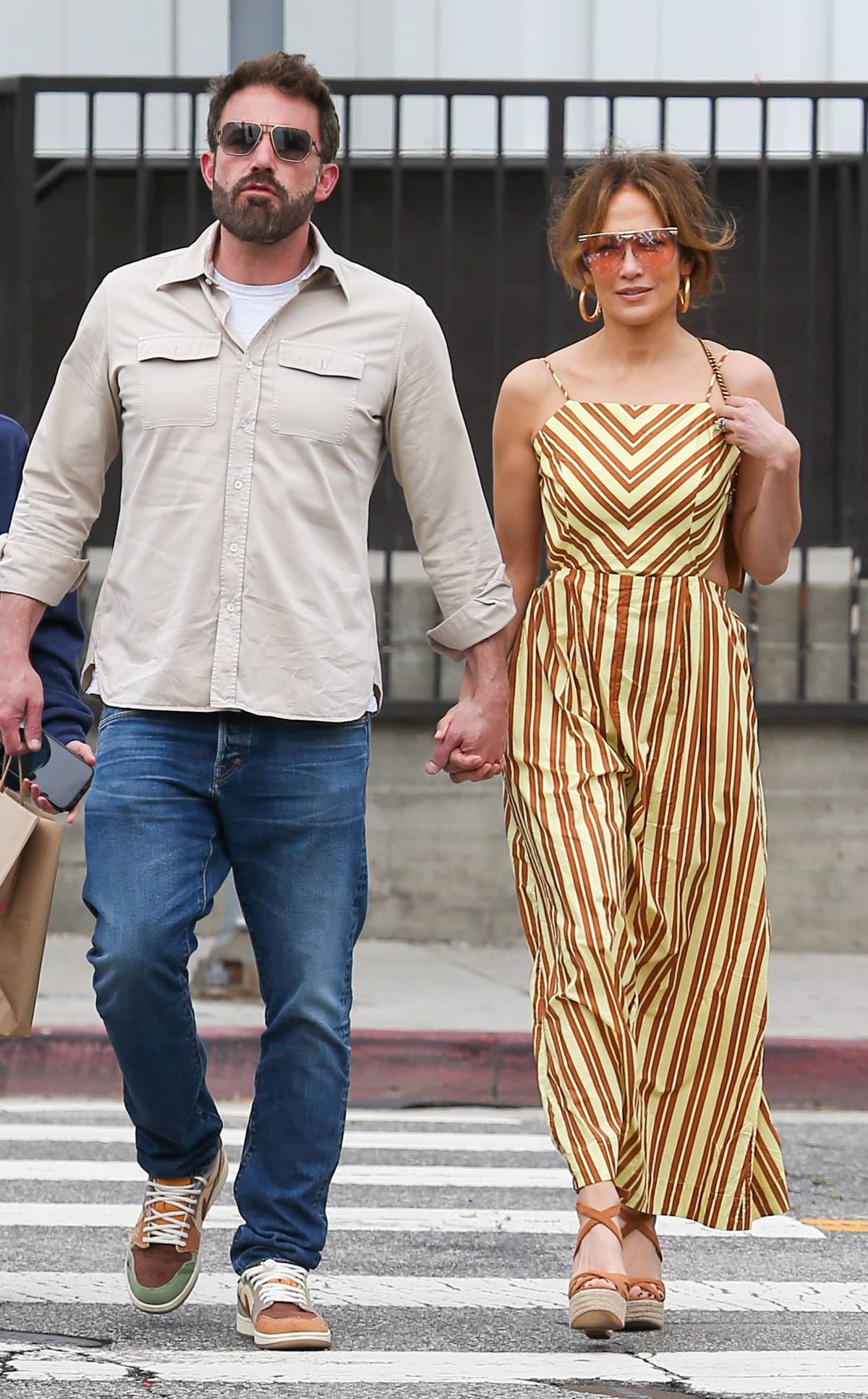 Jennifer Lopez w brązowych espadrylach na koturnie z paskiem wokół kostki, które połączyła z długą sukienką w karmelowe paski