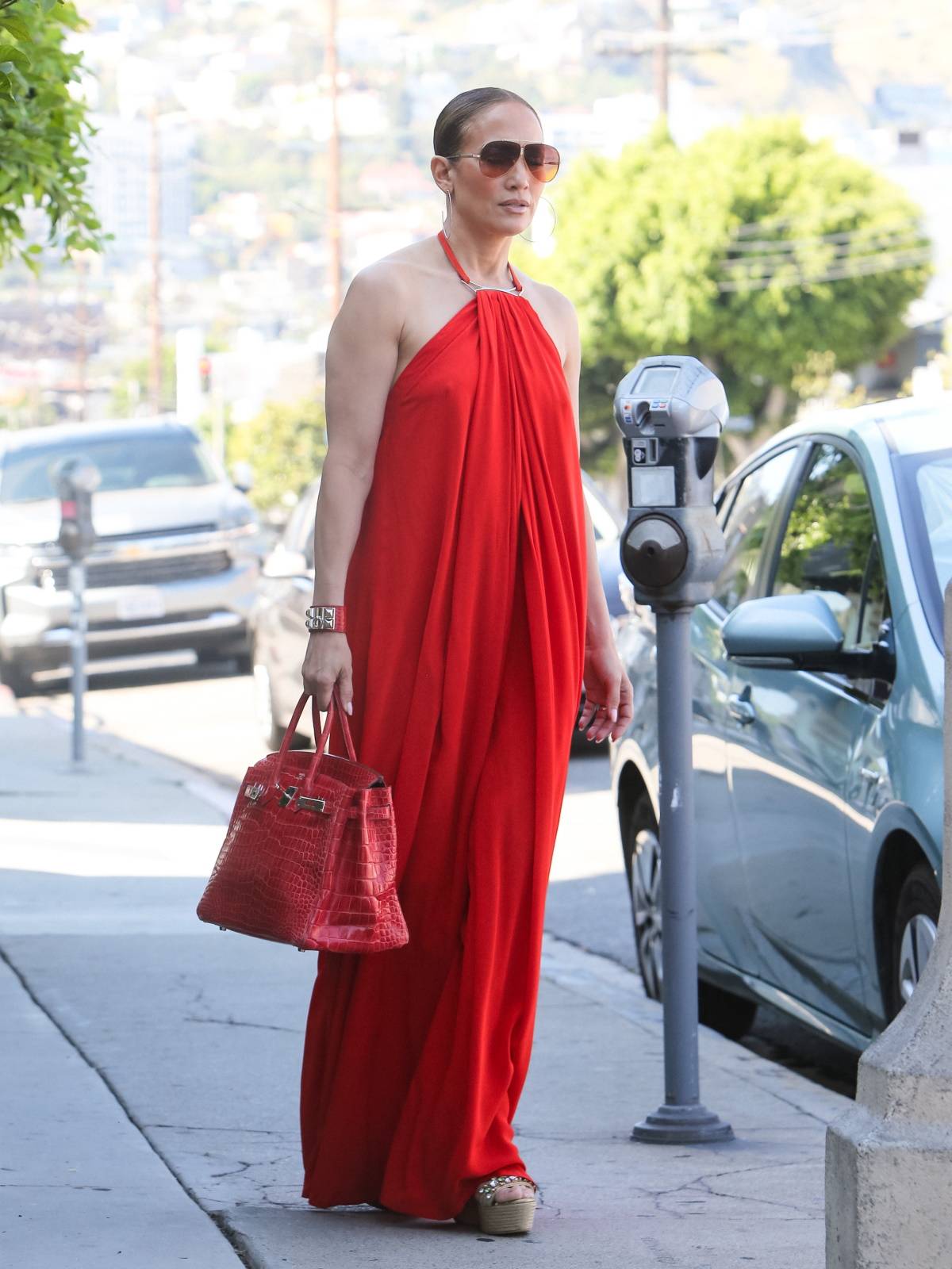 Jennifer Lopez w espadrylach na plecionej podeszwie, które założyła do modnej, czerwonej sukienki maxi z dekoltem halter