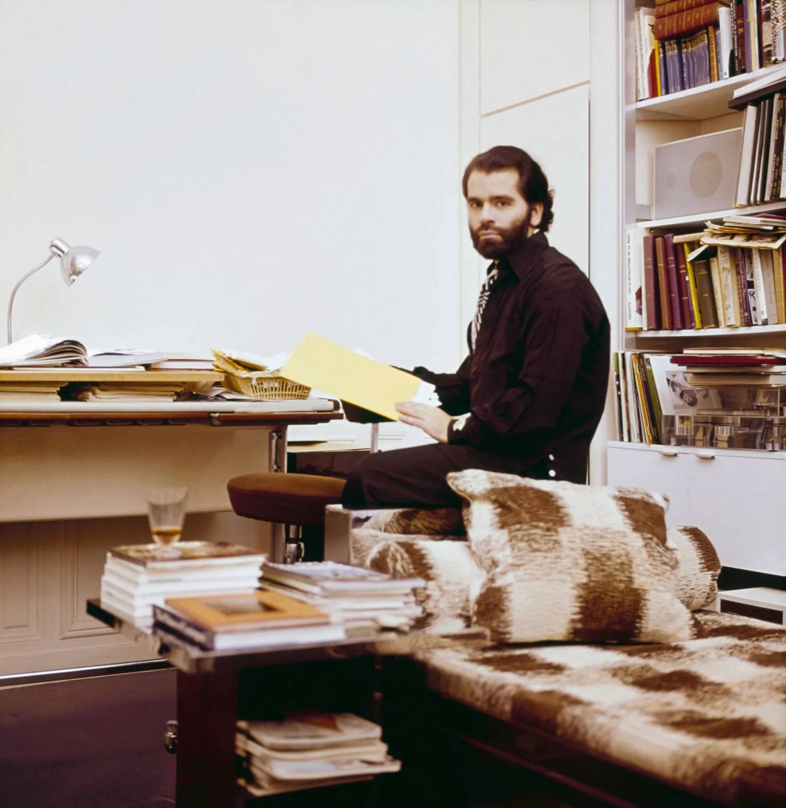 Projektant pozuje przy swoim biurku, na pierwszym planie kryształowy kieli-szek Lalique z coca-colą.