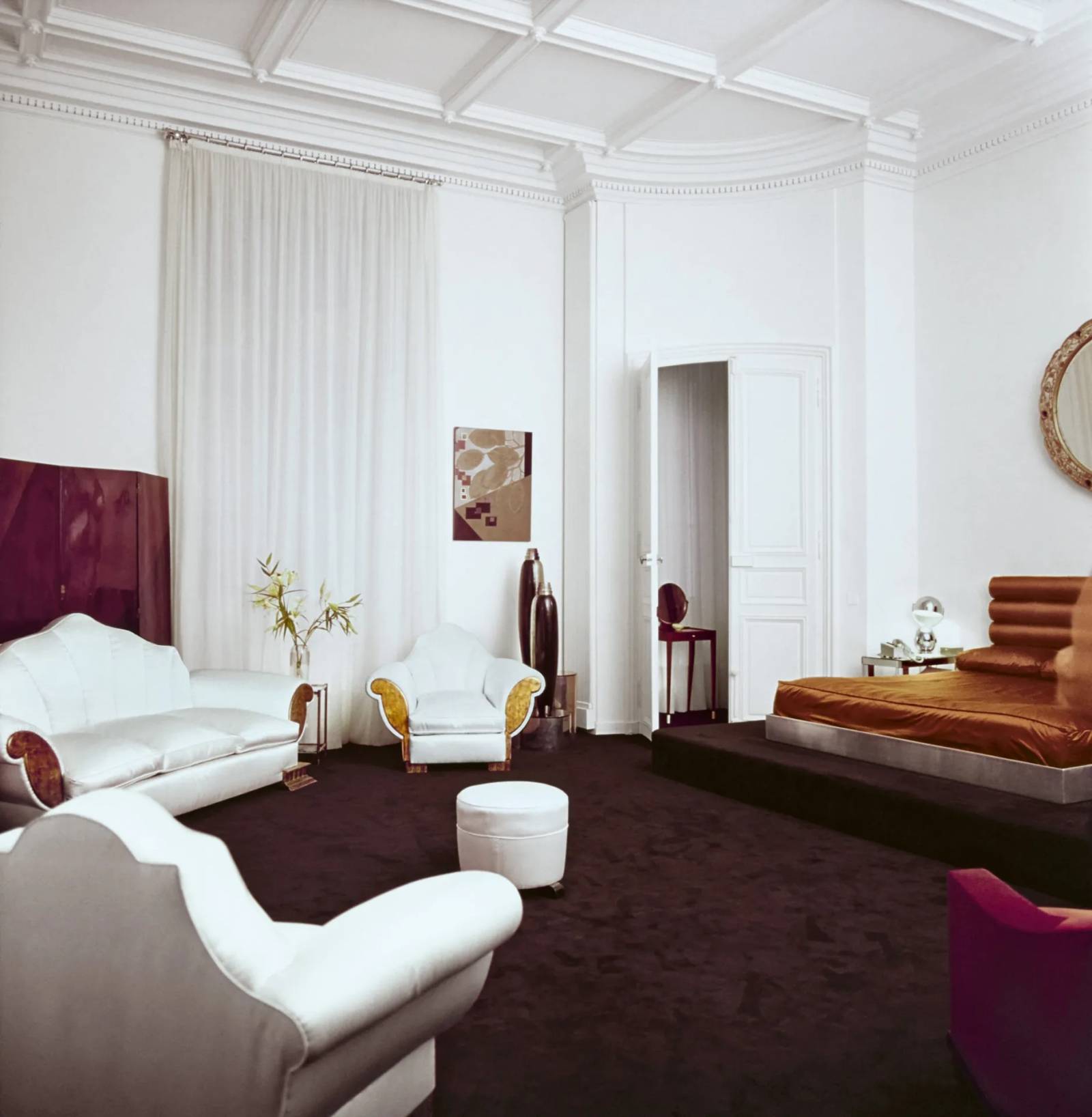 Satynowe fotele Shell i kanapa w kolorze kości słoniowej pochodzą z domu, którego wystrój został zaprojektowany w latach 30. XX wieku przez Elsie de Wolfe, jedną z osób w największym stopniu inspirujących Karla Lagerfelda przy projektowaniu wnętrz. 