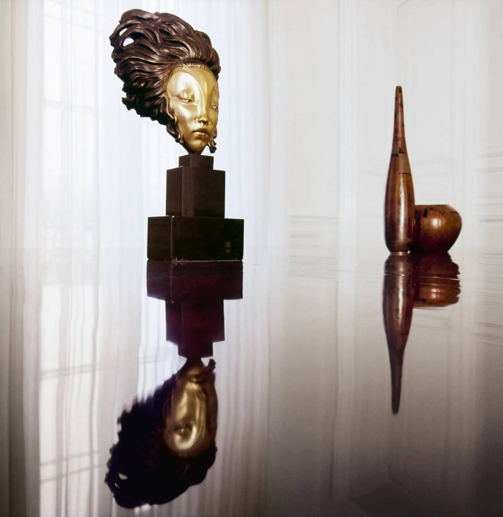 Na dużym lakierowanym stole autorstwa Jacques’a-Émile’a Ruhlmanna i Jeana Dunanda stoi maska z brązu autorstwa Alexandre’a Kéléty’ego na trój-poziomowym piedestale z onyksu oraz para wazonów autorstwa Jeana Du-nanda.