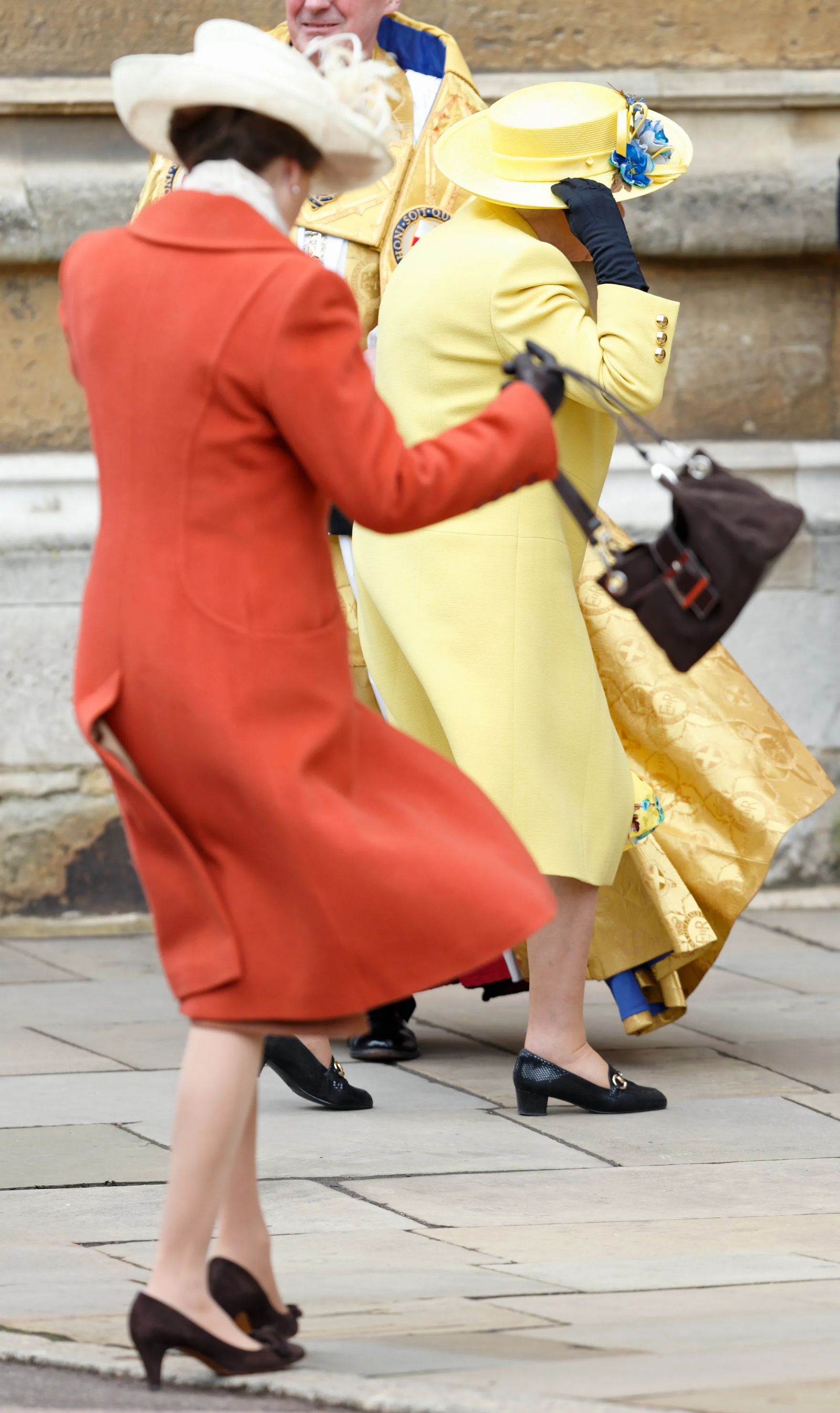 Księżniczka Anna i królowa Elżbieta II trzymają kapelusze podczas podmuchu wiatru w marcu 2016 r.