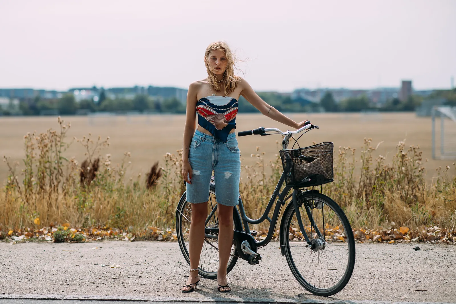 Wzorzysta apaszka noszona jako wiązany top i jeansowe szorty o kroju midi mieszkanki Danii noszą z muszelkową bransoletką na nogę oraz minimalistycznymi sandałkami na kaczuszce.