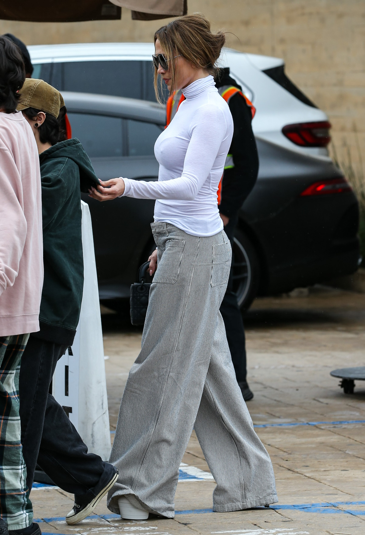Jennifer Lopez w sztruksowych spodniach z szerokimi nogawkami i białym golfie.