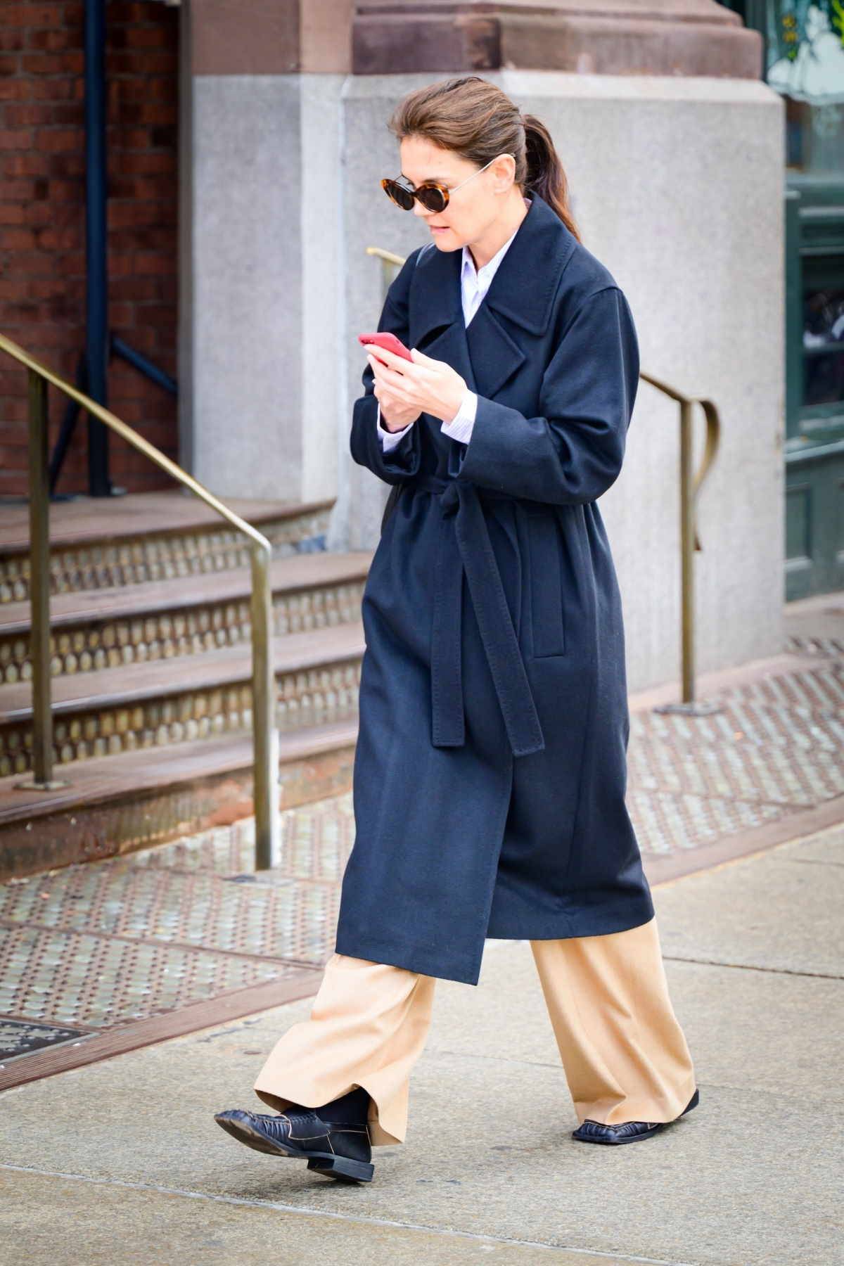 Katie Holmes nosi mokazyny z kwadratowym noskiem z męską garderobą. Katie Holmes w granatowym płaszczu, beżowych spodniach i modnych mokasynach ze ściętym kwadratowym noskiem. Katie Holmes ikoną stylu jest nie tylko z tego powodu.