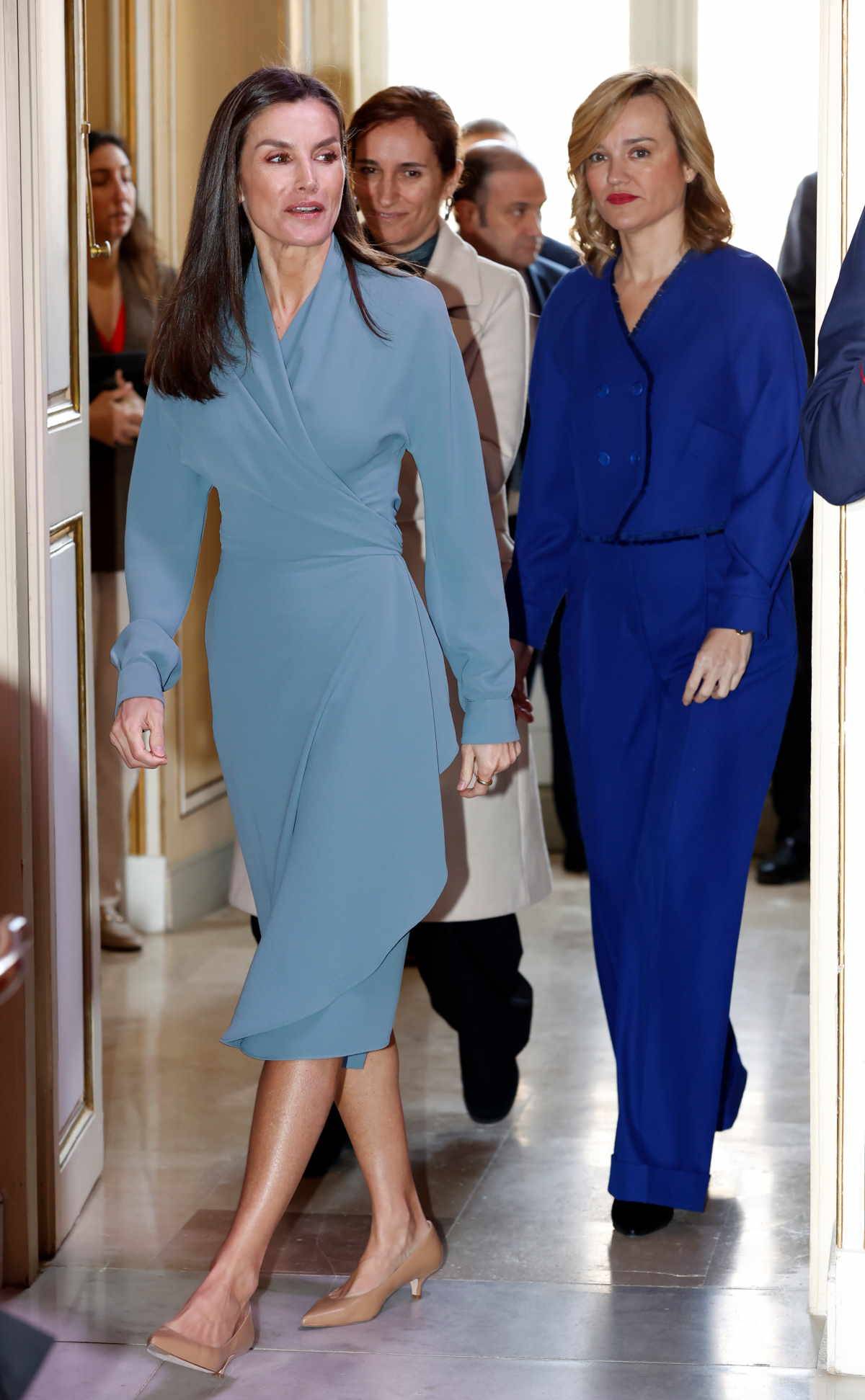 Królowa Letycja w czółenkach na kaczuszce i w niebieskiej sukience kopertowej.