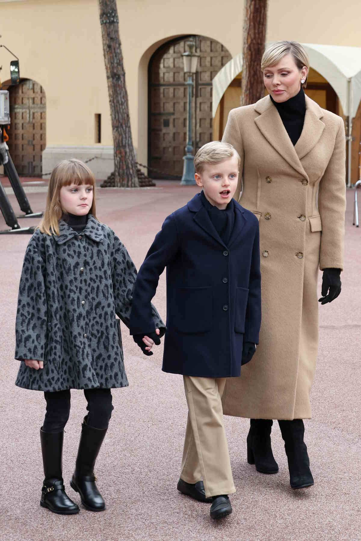 Księżna Charlene w modnym karmelowym płaszczu i kozakach na słupku. 