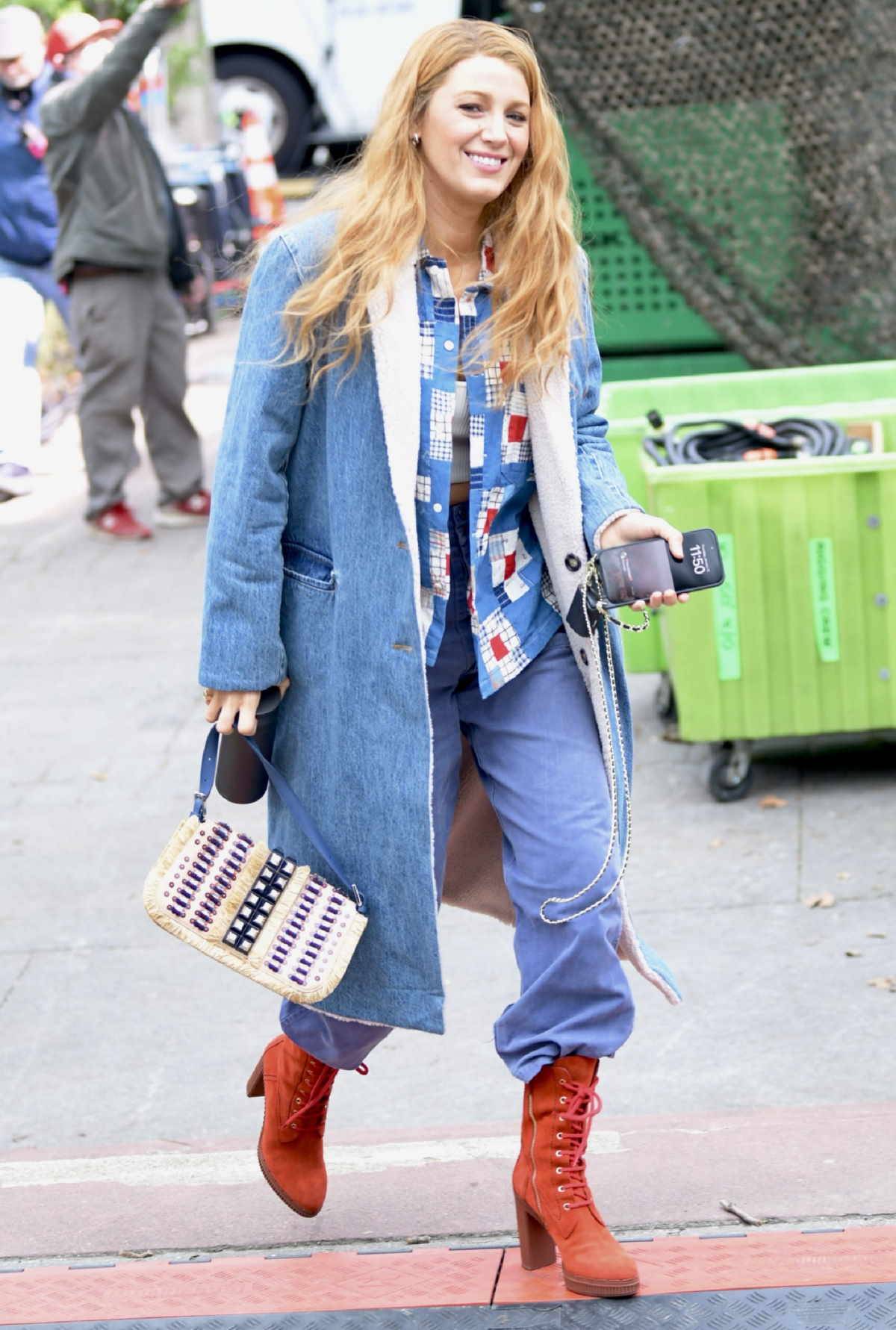 Stylizacja Blake Lively w szerokich jeansach i jeansowym płaszczu, czerwonych botkach na platformie.