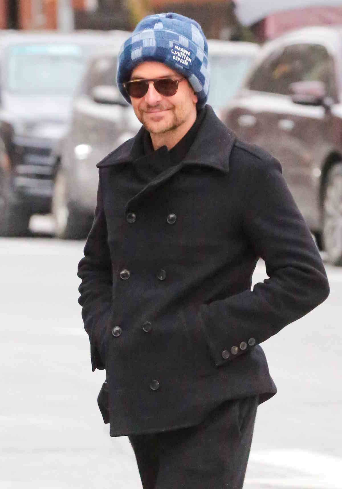 Stylizacja Bradleya Coopera_niebieska czapka Louis Vuitton, szerokie czarne spodnie i sneakersy.