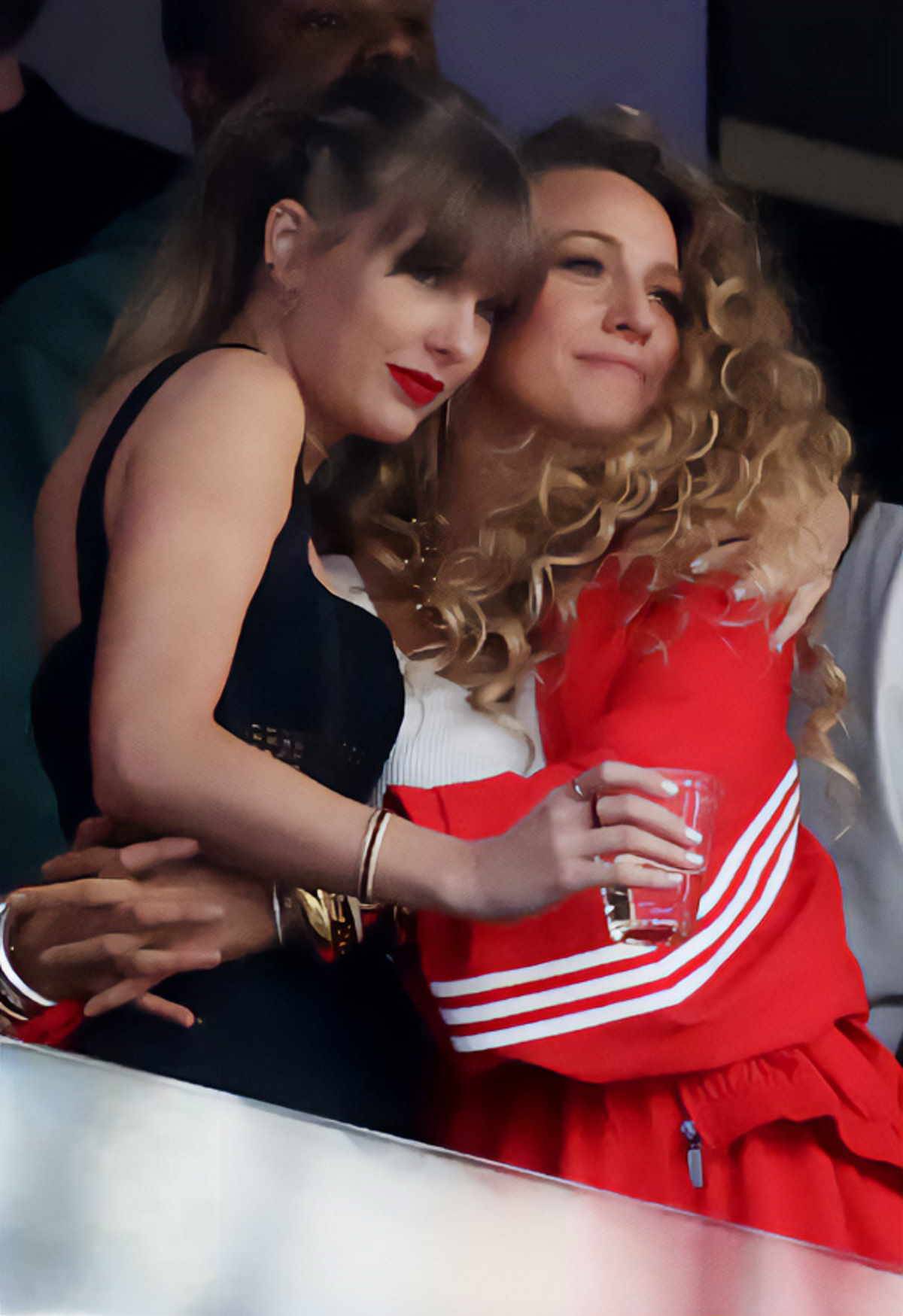 Taylor Swift w czarnych jeansach i Blake Lively w czerwonym kostiumie sportowym marki adidas na Super Bowl.