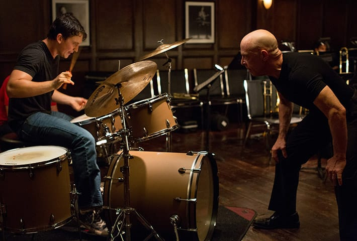 Scena z filmu „Whiplash”, reż. Damien Chazelle, przedstawiająca intensywny trening perkusisty pod okiem wymagającego nauczyciela.