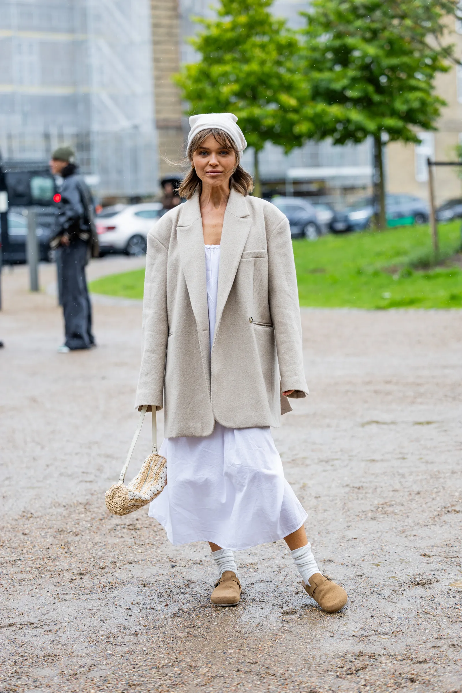 Biała sukienka midi z beżową marynarką oversize, białymi skarpetkami i jasnobrązowymi butami Birkenstock Boston. (Fot. Christian Vierig/Getty Images)