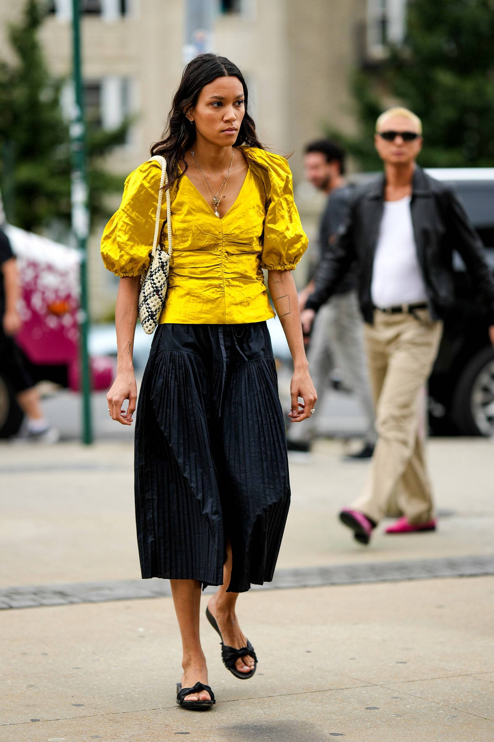 Street style proponuje zestawienie satynowej bluzki damskiej z rękawem 3/4 z plisowaną spódnicą (Fot. Getty Images)