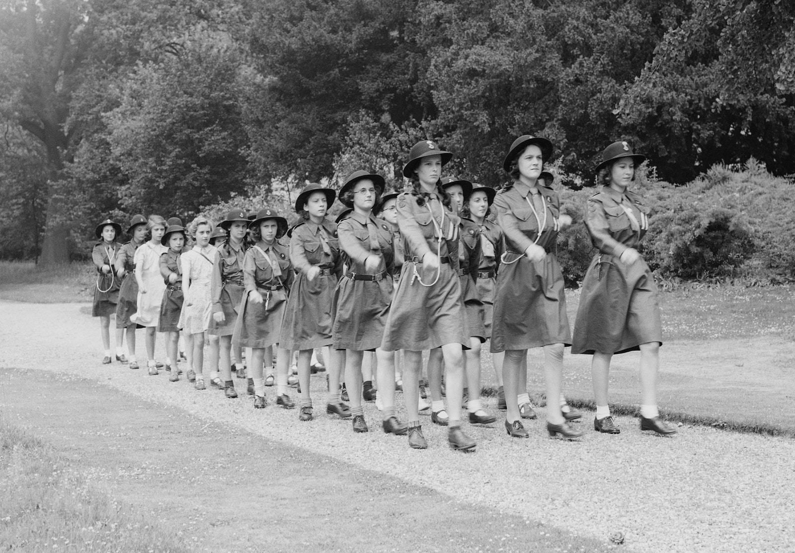 Jej Wysokość w czasie ćwiczeń ze złożonym z uchodźczyń oddziałem Girl Guides w Windsorze w czasie wojny. „Uchodźczynie nie okazywały wobec przyszłej królowej żadnej uległości, nazywając ją Lilibet, przezwiskiem, którego nie wolno było używać nawet córkom arystokratów, zmuszając ją do mycia naczyń w miednicy pełnej tłustej wody i sprzątać zwęglone pozostałości po ogniskach”, pisze Sally Bedell Smith w książce „The Queen”. 
Lisa Sheridan/Getty Images