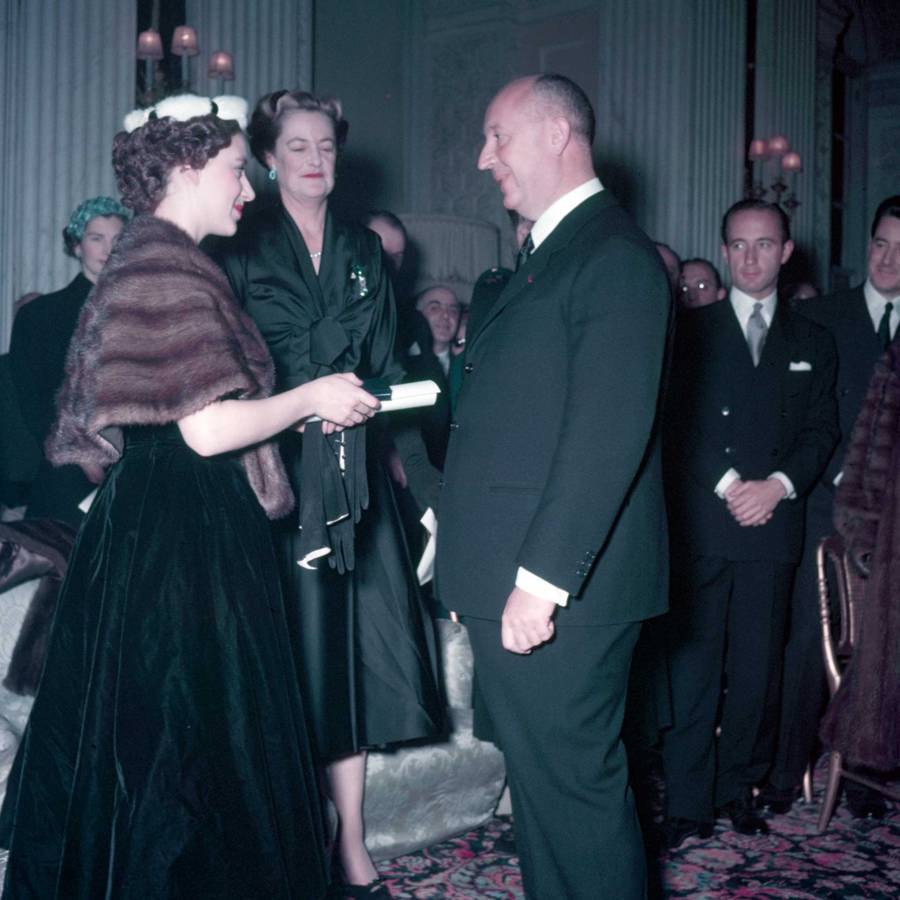 Princess Margaret (left), with the Duchess of Marlborough (second from left), presents Christian Dior with a scroll entitling him to Honorary Life Membership of the British Red Cross after the presentation of his Winter Collection at Blenheim Palace on 3rd November 1954. Credit: 
POPPERFOTO / GETTY IMAGES