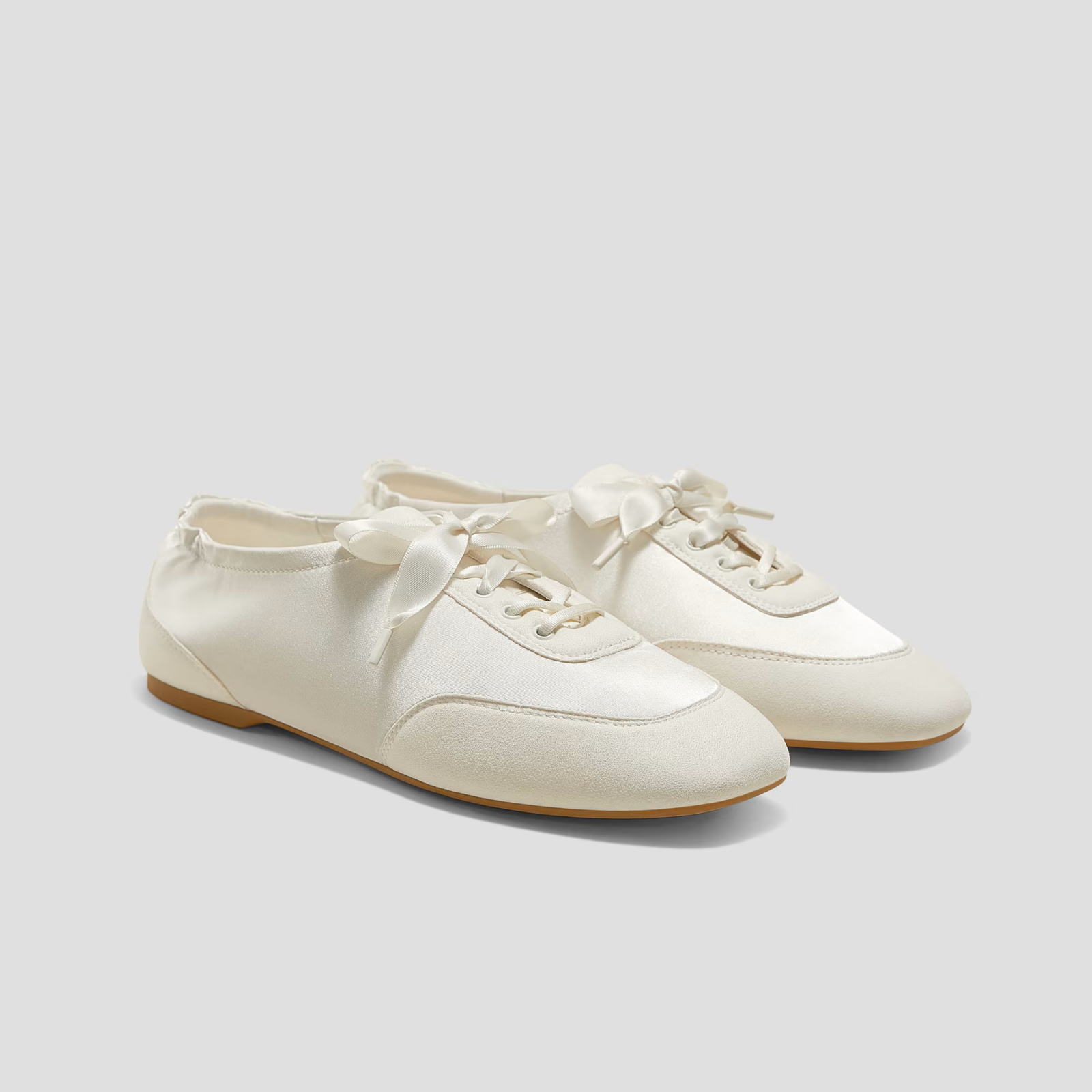 Eleganckie, satynowe sneakersy w kolorze białym, z delikatnymi kokardkami i płaską podeszwą.