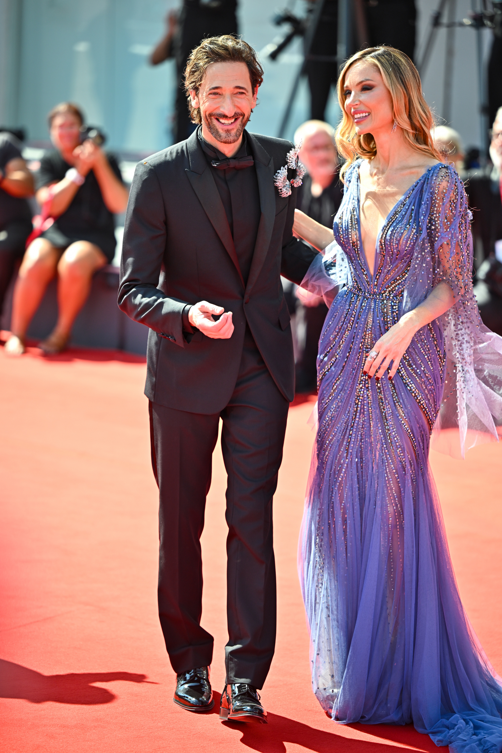 Adrien Brody i Georgina Chapman na premierze "Brutalisty" na Festiwalu Filmowym w Wenecji, uśmiechnięci na czerwonym dywanie.