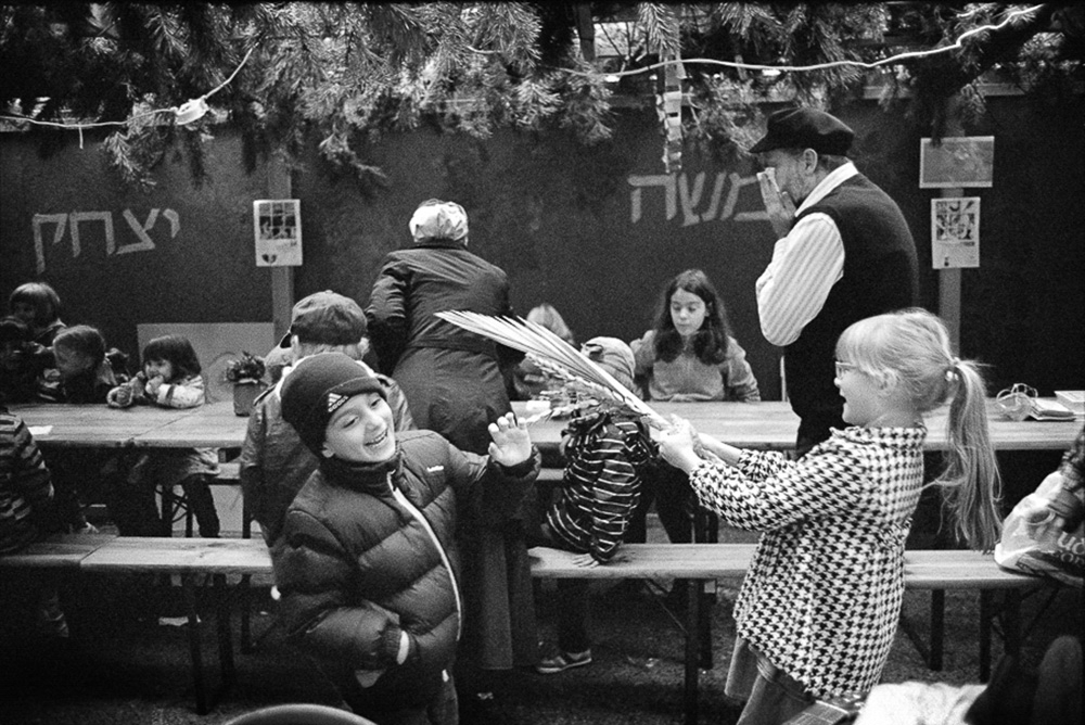 Szałas na Sukot przy Synagodze Nożyków w Warszawie. Dzieci bawią się lulawem i etrogiem. 2013  rok (Fot. Chuck Fishman)