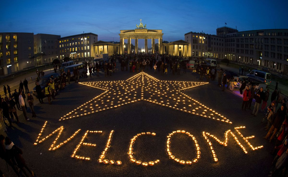 Świeczki ułożone w napis „Welcome” – skierowany do uchodźców. W tle Brama Brandenburska (Fot. JOHANNES EISELE, AFP/EAST NEWS)