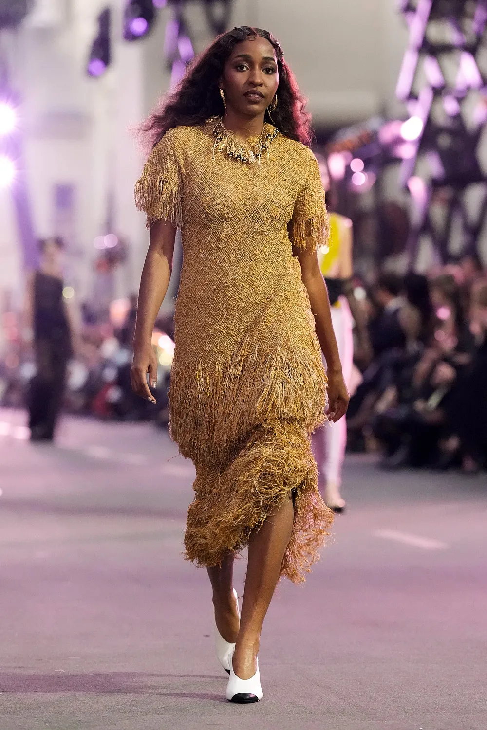 Ayo Edebiri na Vogue World 2025 w złotej sukni Chanel  z frędzlami, elegancko kroczy po wybiegu.