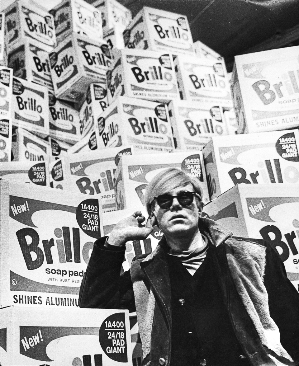 Andy Warhol na tle pudełek Brillo, wystawa w Poznaniu, 1960-te lata. To ikoniczny obraz pop-artu.