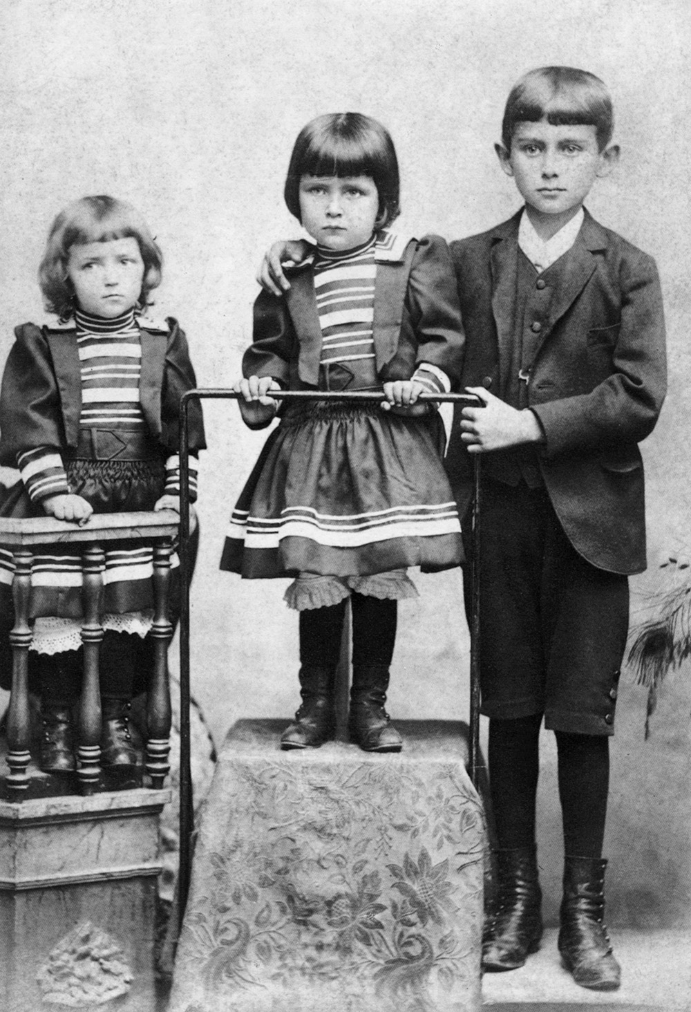 Franz Kafka z siostrami, stojącymi w eleganckich strojach, na zdjęciu z dzieciństwa.