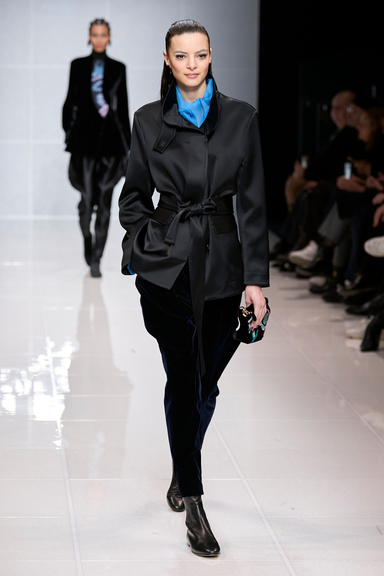 Modelka idzie po wybiegu w marynarce z paskiem od Giorgio Armani, zestawionej z niebieską bluzką i aksamitnymi spodniami.