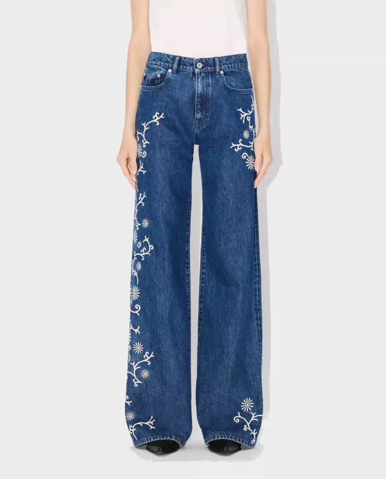 Damskie jeansy boho z szerokimi nogawkami, zdobione białym haftem roślinnym.