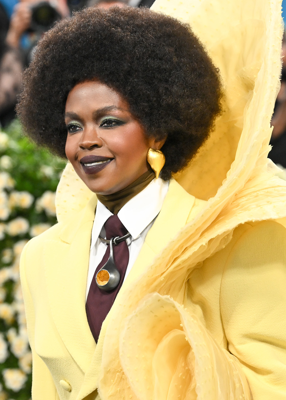 Lauryn Hill z kultową Birkin bag, w żółtej stylizacji z dużym kapeluszem i afro fryzurą.