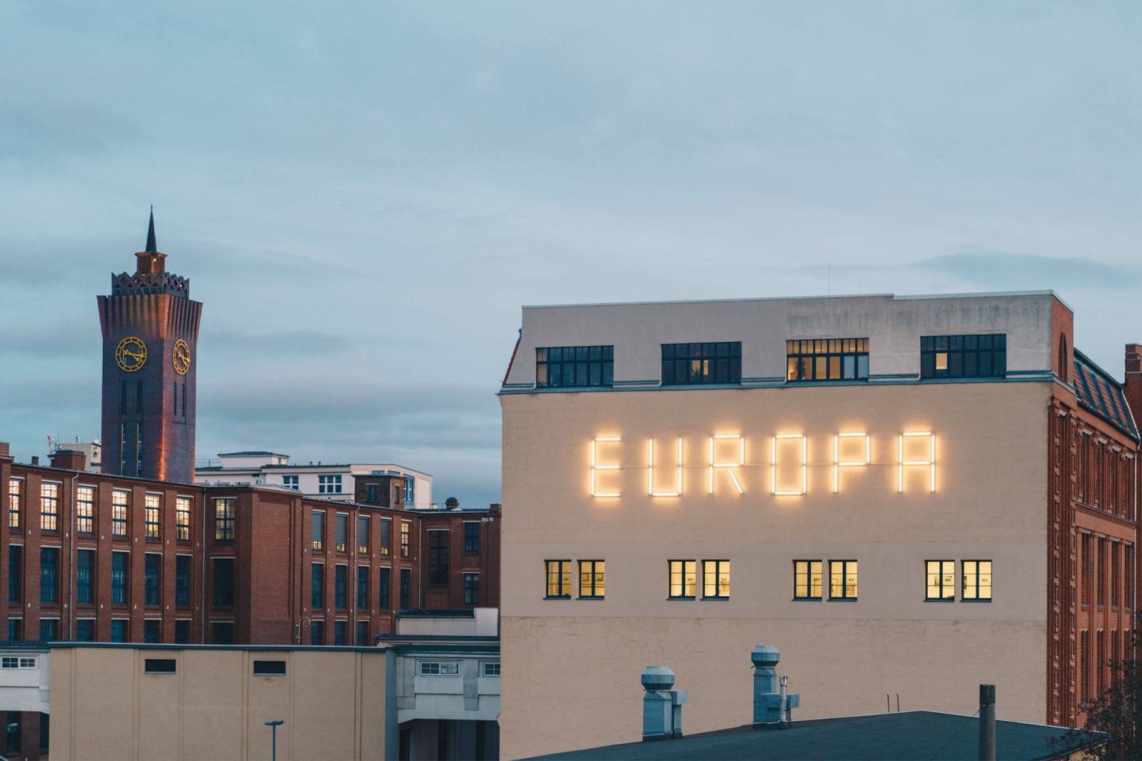 Widok na budynki w Chemnitz, z podświetloną nazwą "EUROPA" na jednej z elewacji oraz wieżą w tle.