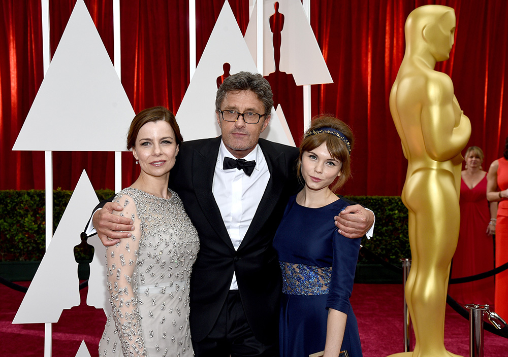 Na czerwonym dywanie stoją Paweł Pawlikowski oraz dwie kobiety, uśmiechając się do aparatu w eleganckich strojach.