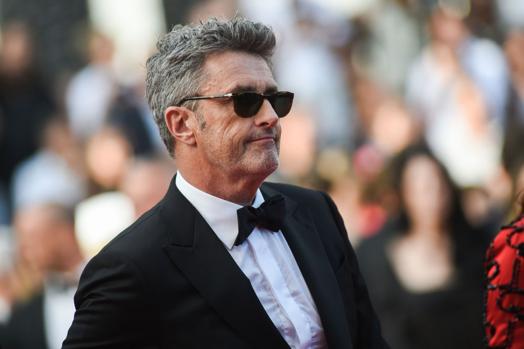Paweł Pawlikowski na czerwonym dywanie, w eleganckim garniturze i okularach przeciwsłonecznych.