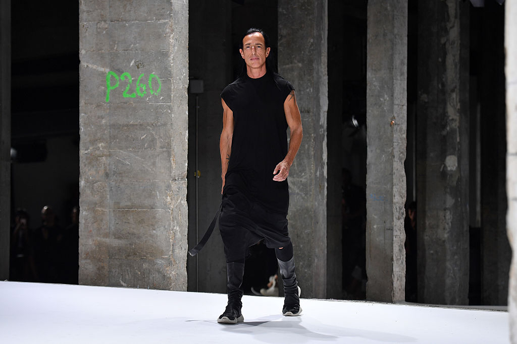 Rick Owens na wybiegu, prezentujący minimalistyczną, czarną stylizację w industrialnym otoczeniu.