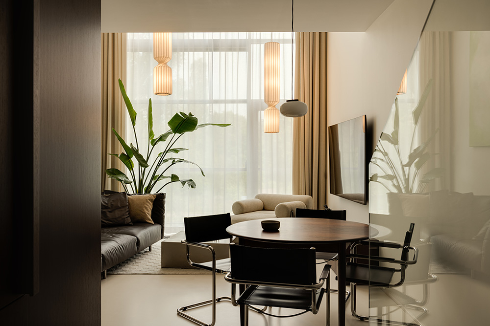 Stylowe wnętrze z dużymi oknami, roślinnością, nowoczesnym stołem i wygodną kanapą. Jasne kolory i minimalistyczny design.