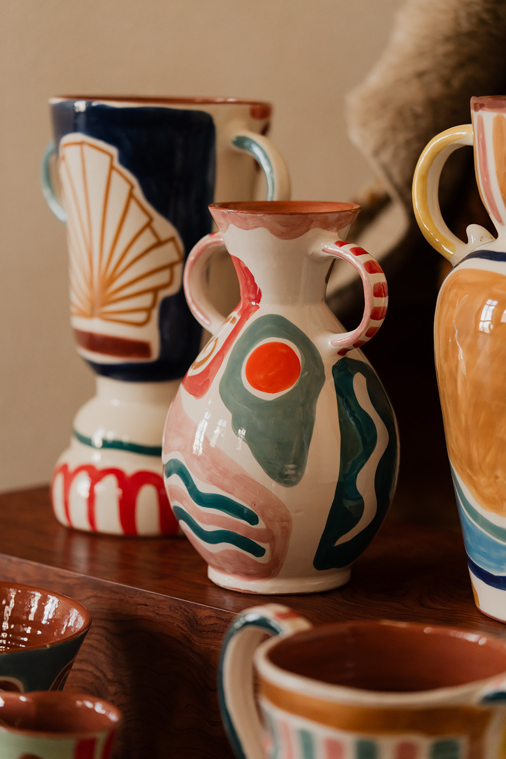 Kolorowe wazoniki ceramiczne w różnych kształtach i wzorach, ustawione na drewnianym tle.