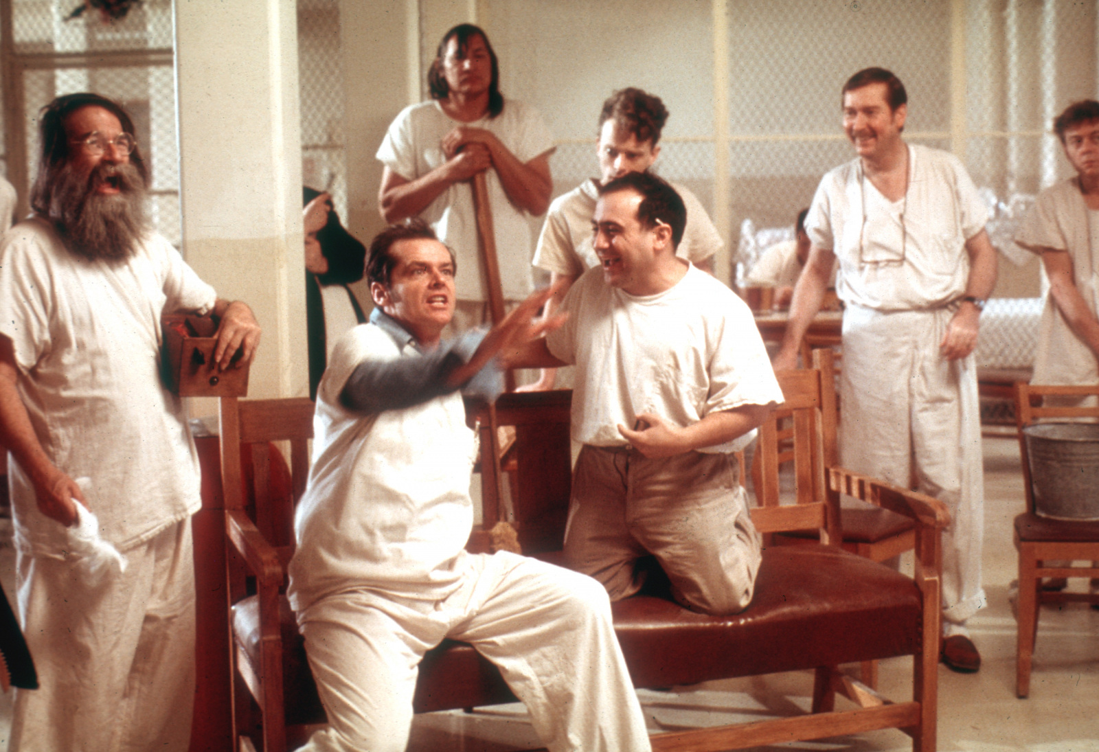 Scena z filmu "Lot nad kukułczym gniazdem", gdzie pacjenci rozmawiają, a jeden z nich wyraża swoje emocje.