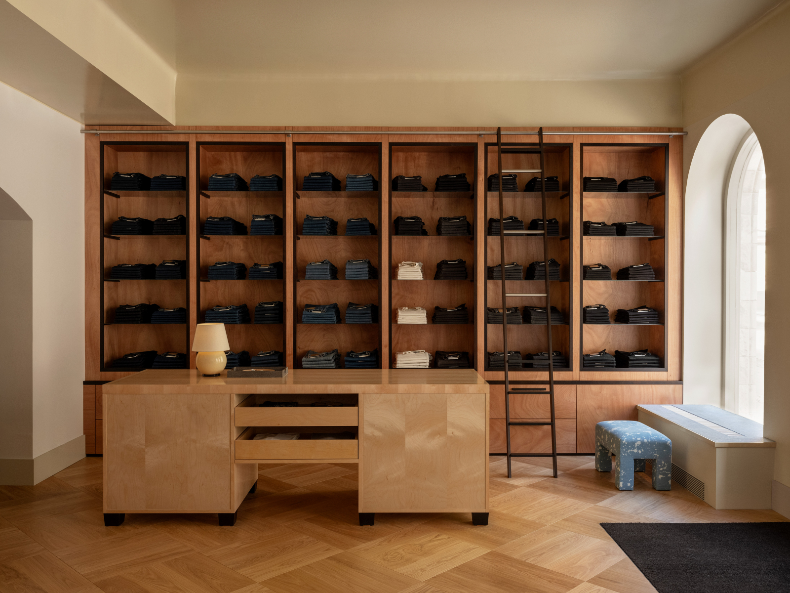 Butik Jeanerica z eleganckim wnętrzem, w którym znajdują się regały z denimem oraz minimalistyczne meble.