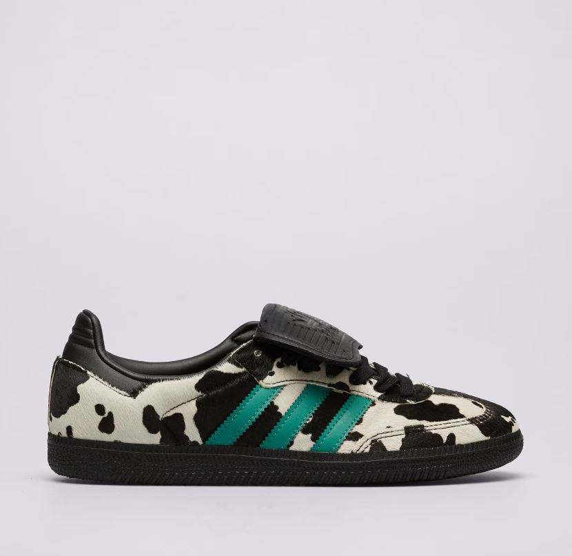 Sneakersy w krowie łaty marki Adidas w kolorze białym i czarnym z zielonymi trzema paskami.