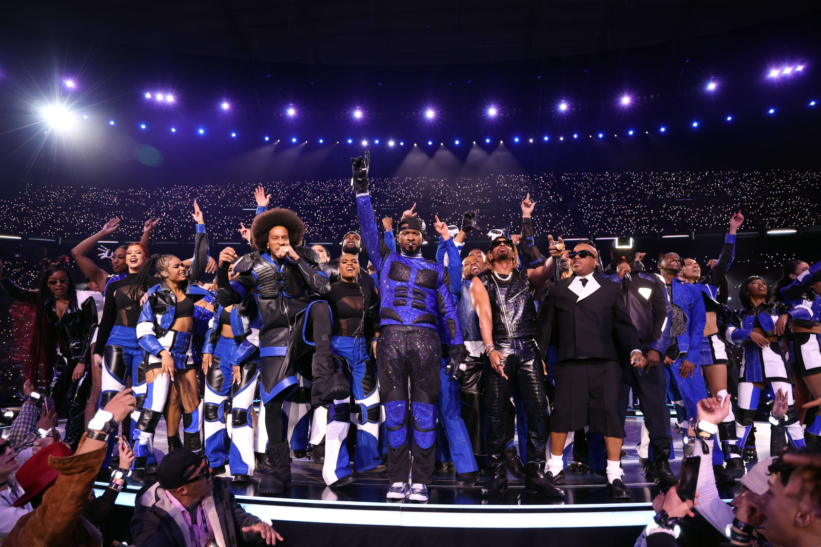 Usher i zespół występują na scenie podczas Super Bowl, z energicznym tańcem i efektowną choreografią.