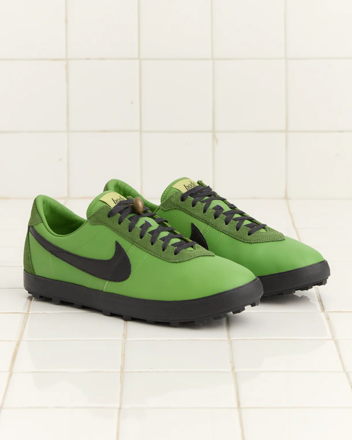 Zielone sneakersy Nike z czarnymi detalami, umieszczone na jasnej, kafelkowej powierzchni.