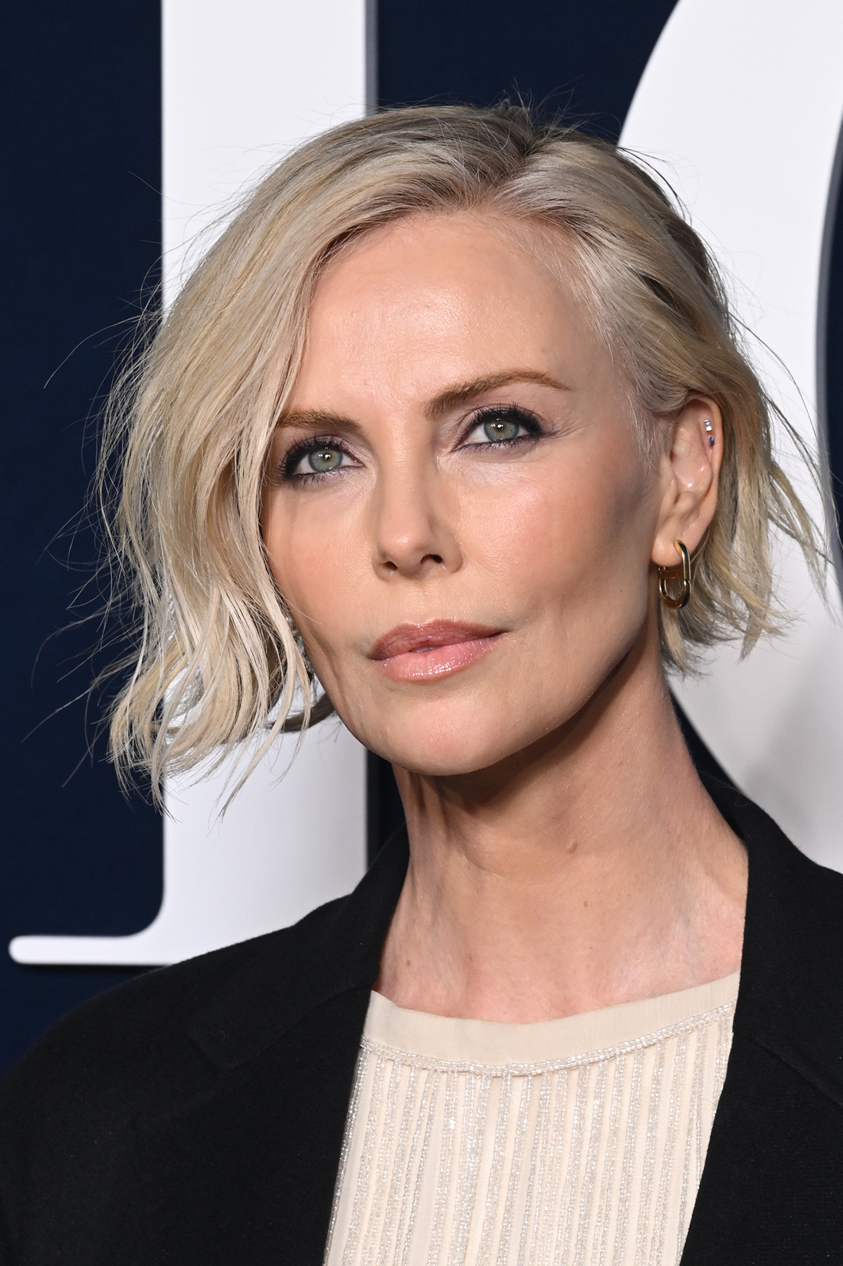 Charlize Theron w kremowym topie i czarnej marynarce.