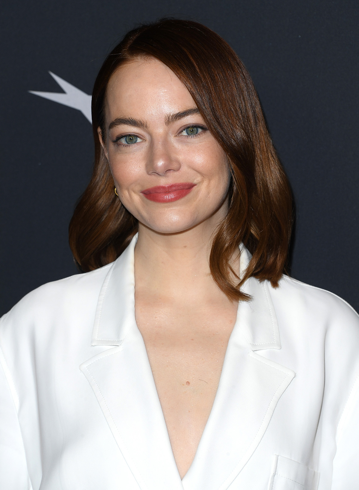 Emma Stone w białej marynarce i z włosami do ramion.