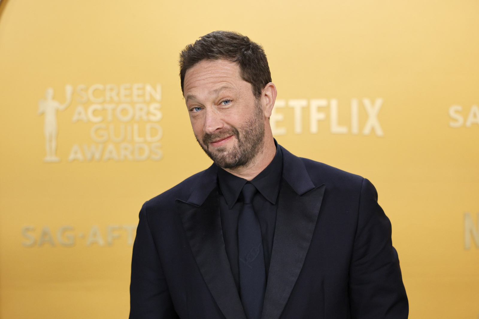 Ebon Moss-Bachrach podczas gali SAG Awards w 2025 roku, uśmiechnięty w eleganckim garniturze.