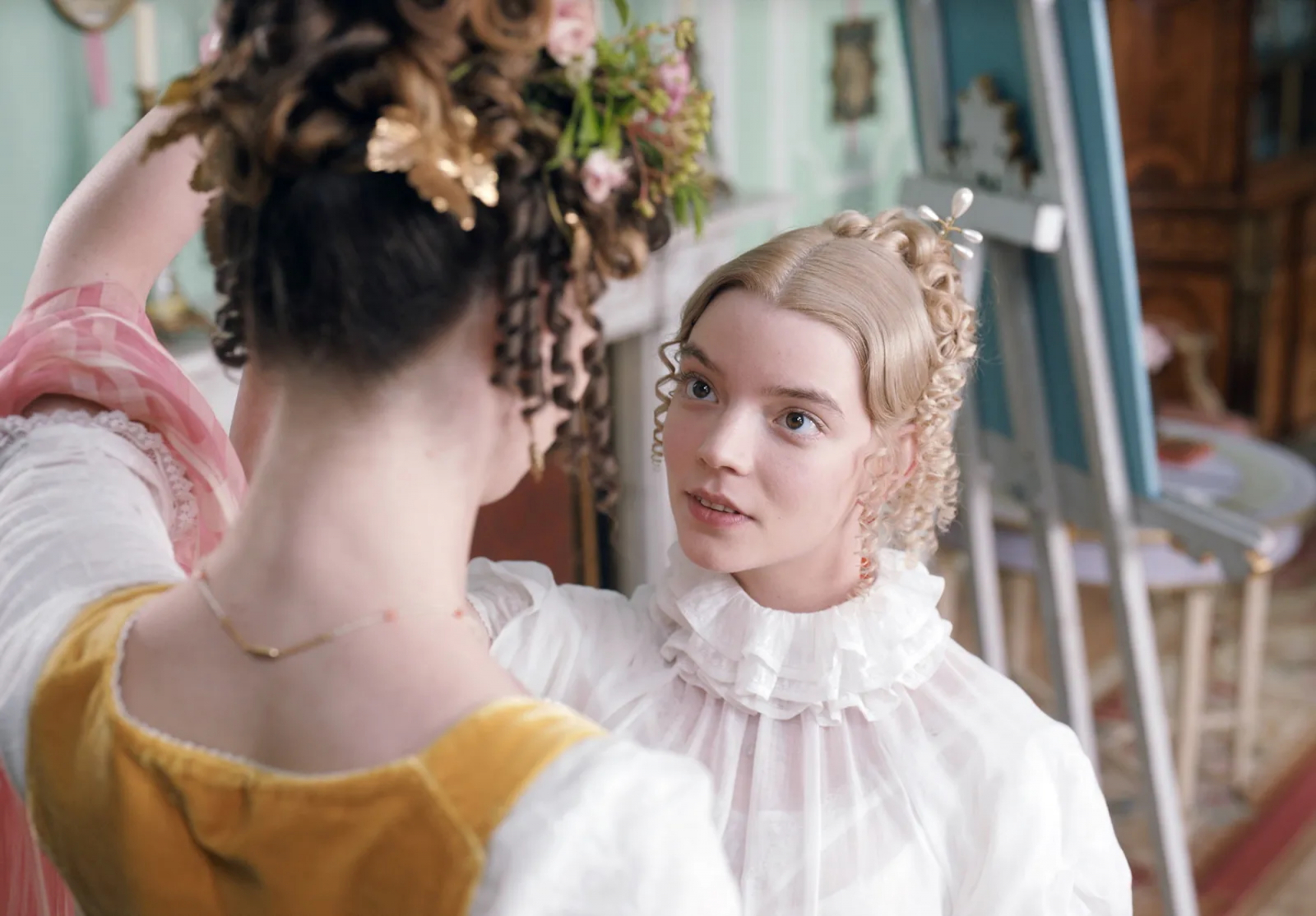 Anya Taylor-Joy w filmie „Emma”. Scena zdobienia włosów, ukazująca eleganckie stroje i stylistykę epoki.