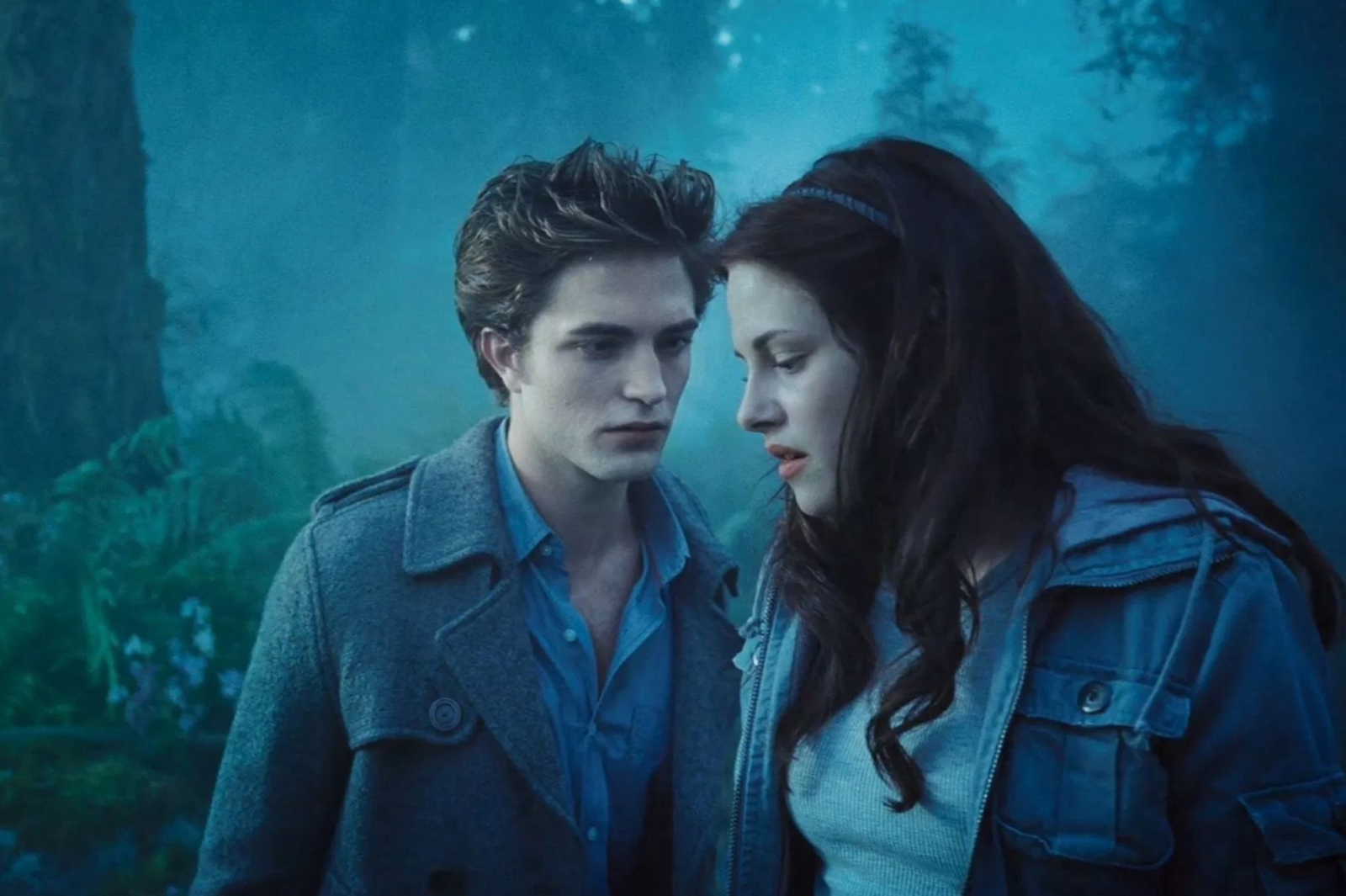 Robert Pattinson i Kristen Stewart w emocjonalnym kadrze z filmu „Zmierzch”, otoczeni mgłą w lesie.