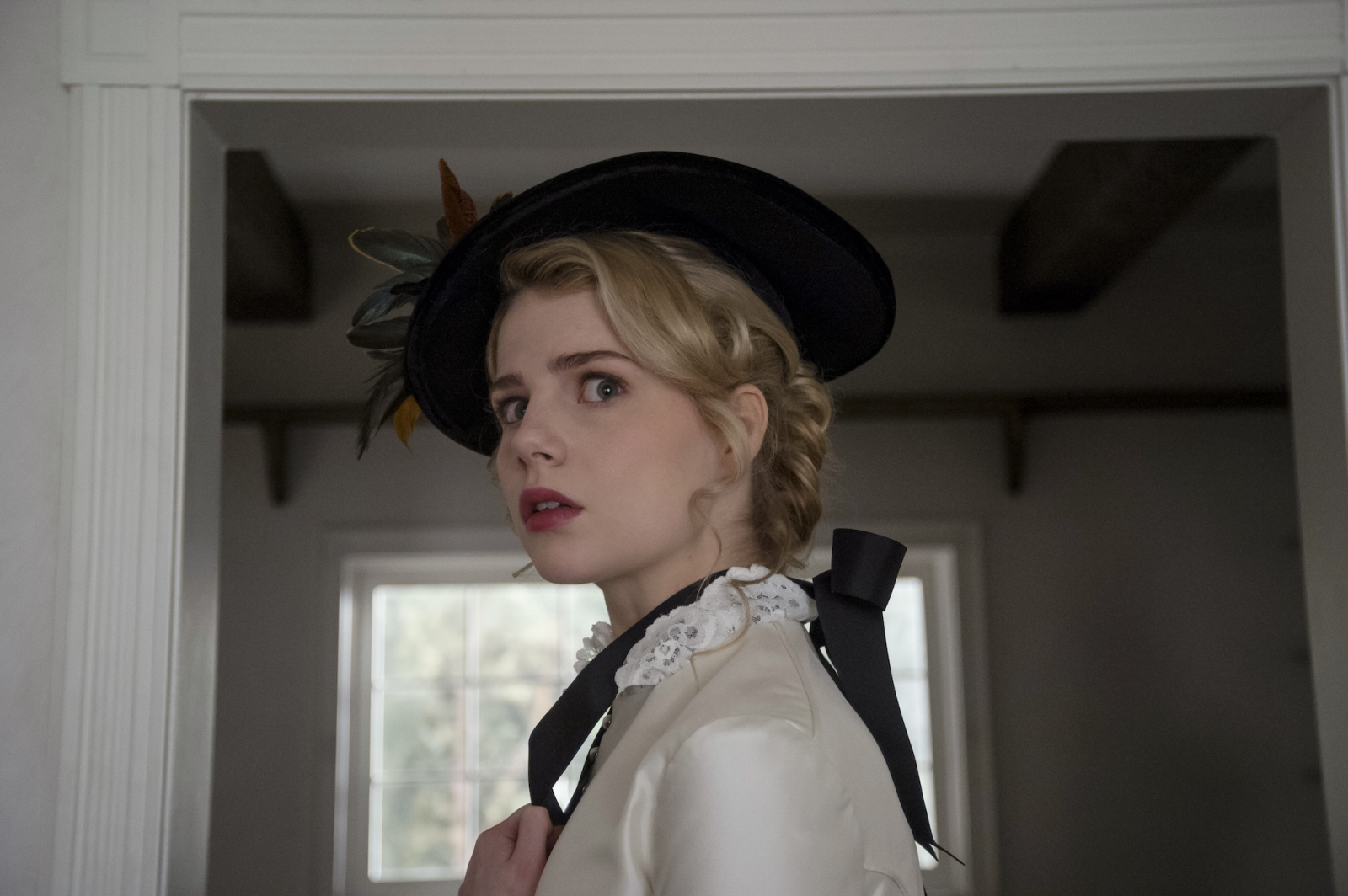 Kadr z filmu grozy Netflix „I Am the Pretty Thing That Lives In the House”, przedstawiający zaniepokojoną kobietę w modnym kapeluszu.