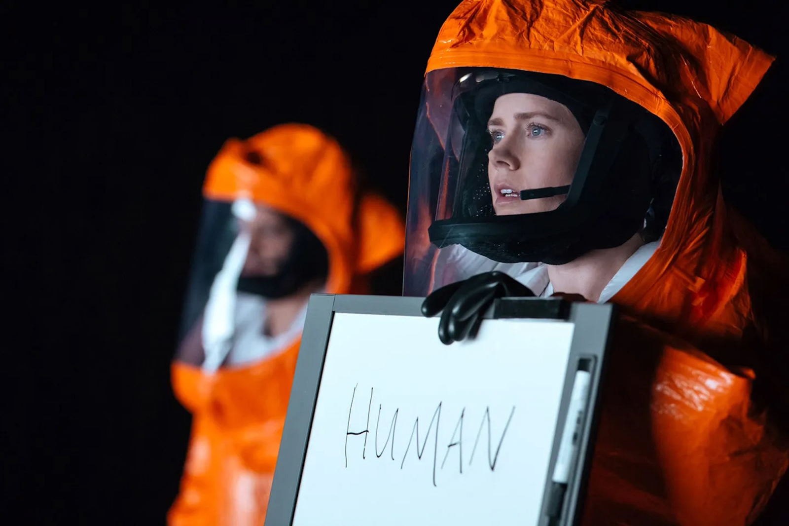 Amy Adams w filmie „Nowy początek” w skafandrze, trzymająca tablicę z napisem „HUMAN”.